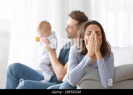 Heureux père avec son bébé et sa femme souffrant de dépression postnatale à la maison Banque D'Images