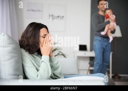 Heureux père avec son bébé et sa femme souffrant de dépression postnatale à la maison Banque D'Images