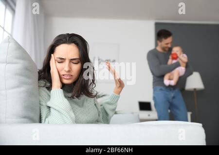 Heureux père avec son bébé et sa femme souffrant de dépression postnatale à la maison Banque D'Images