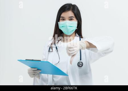 Jeune femme de médecin asiatique portant un pelage uniforme de robe de médecin , masque médical et stéthoscope tenant un presse-papiers regardant malheureux et fâché montrant le rejet Banque D'Images