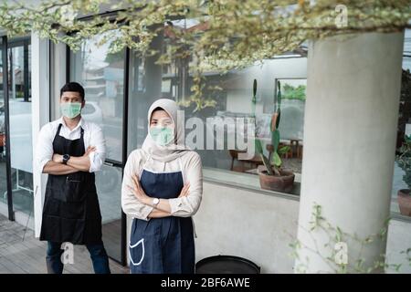 le travailleur de café musulman porte des masques de visage devant la boutique Banque D'Images