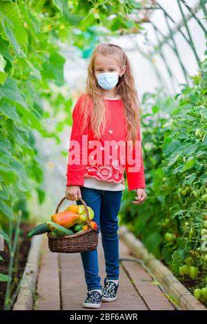 Cute little girl recueille les concombres et tomates de serre en Banque D'Images