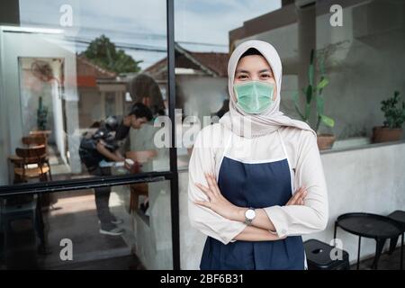 le travailleur de café musulman porte des masques de visage devant la boutique Banque D'Images