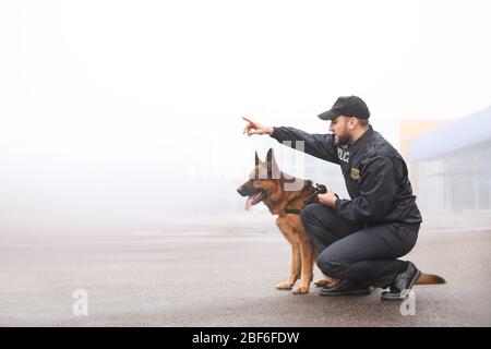 Policier masculin avec rue de ville de patrouille de chien Banque D'Images