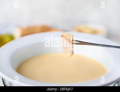 Trempez le crouton dans la fondue au fromage, la fermeture Banque D'Images