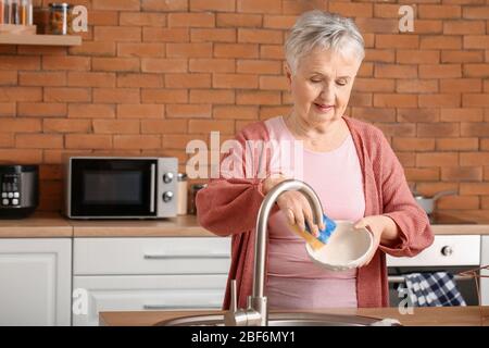 Senior woman washing dishes in kitchen Banque D'Images