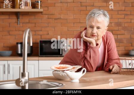 Femme senior avec des plats sales dans la cuisine Banque D'Images