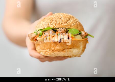 Femme avec un bebab de beignet savoureux dans un petit pain, près Banque D'Images