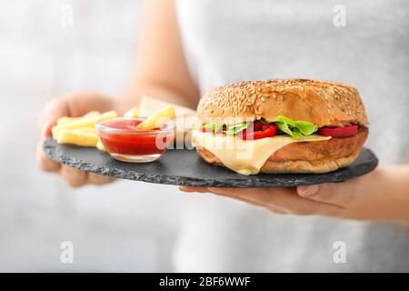 Femme avec un délicieux bebab de beignets dans un pain, des frites et de la sauce, gros plan Banque D'Images