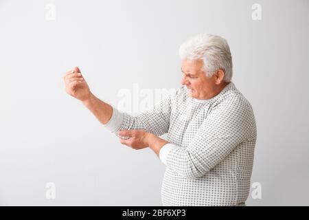 Homme senior souffrant du syndrome de Parkinson sur fond gris Banque D'Images