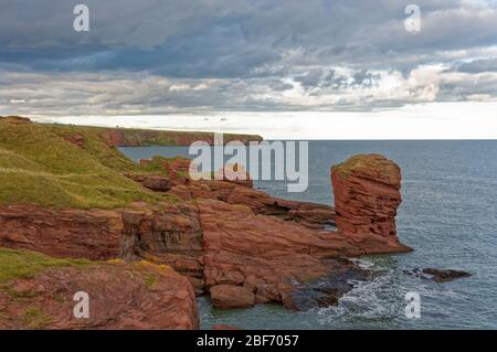 La mer de Heid de Deil se pile sur le sentier côtier d'Arbroath sur la côte est de l'Écosse avec des nuages sombres au-dessus. Banque D'Images