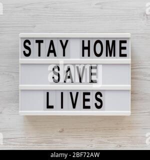 « Stay Home Save Lives » mots sur un tableau moderne sur fond blanc en bois, vue de dessus. En hauteur, par dessus, plat. Banque D'Images