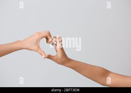 Femme et enfant faisant le coeur avec leurs mains sur fond gris. Concept de charité Banque D'Images