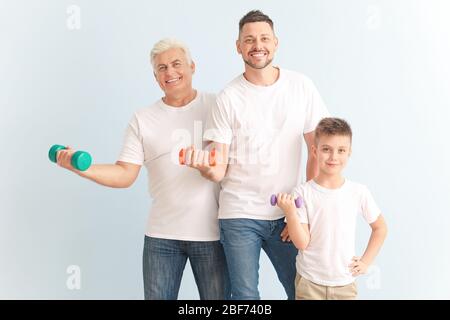 Homme avec son père et son fils tenant des haltères sur fond de couleur Banque D'Images