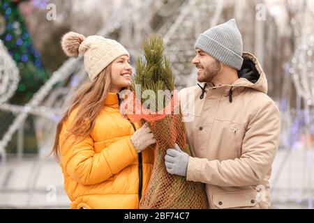 Jeune couple avec arbre de Noël acheté à l'extérieur
