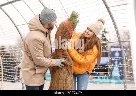 Jeune couple avec arbre de Noël acheté à l'extérieur