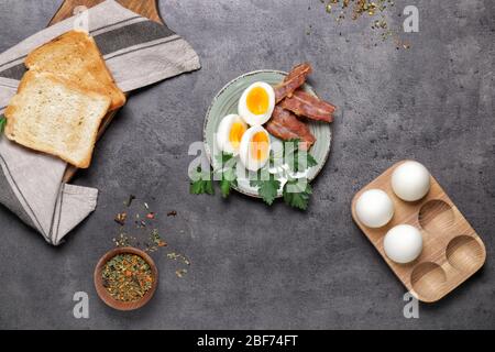 Assiette avec œufs durs, bacon et pain grillé sur fond sombre Banque D'Images