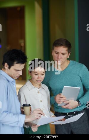 Groupe de jeunes collègues d'affaires lisant des documents et préparant la présentation ensemble au bureau Banque D'Images