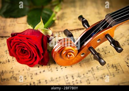 musique classique rétro pour violon chaîne instrutt sur la vieille musique note papier avec fleur de rose rouge sur fond de bois de chêne ancien. musique classique rom Banque D'Images