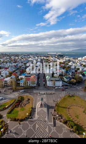 Vue de l'église Hallgrímskirkja de Reykjavík, Islande, montrant des maisons colorées, un ciel bleu avec des nuages blancs et gris, et le port Banque D'Images