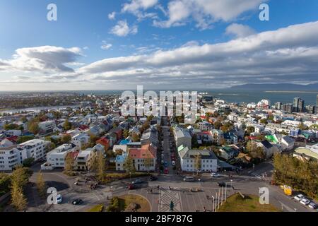 Vue de l'église Hallgrímskirkja de Reykjavík, Islande, montrant des maisons colorées, un ciel bleu avec des nuages blancs et gris, et le port Banque D'Images