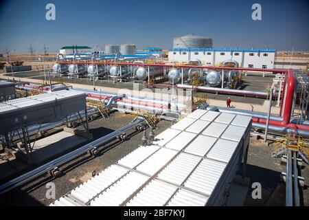 Panorama de l'usine de raffinerie de pétrole dans le désert. Ouvrier en casque blanc et en vêtements de travail rouges. Échangeurs thermiques, réservoirs de stockage de pétrole, canalisations et construction d'usines. Banque D'Images