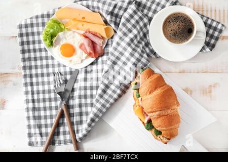 Délicieux sandwich croissant avec café et œufs frits sur la table Banque D'Images