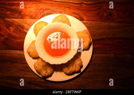 La cuisine végétarienne de Momos est servie avec du chutney de tomates sur fond de bois. Banque D'Images