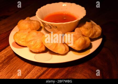 La cuisine végétarienne de Momos est servie avec du chutney de tomates sur fond de bois. Banque D'Images