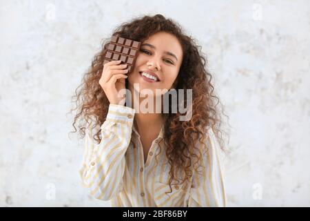 Jeune femme afro-américaine avec chocolat sur fond clair Banque D'Images