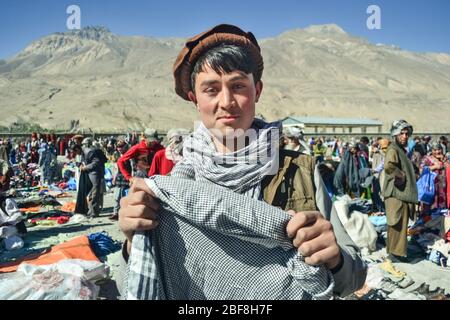 Ischkashim / Afghanistan - 5 octobre 2013: Beau Pachtoun afghan jeune homme sourie tenant le foulard sur le marché afghan entre le Tadjikistan et l'Afghanistan Banque D'Images