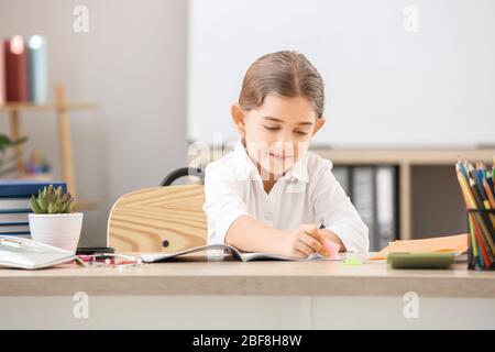 Mignonne petite écolière qui fait de la tâche à la réception en classe Banque D'Images