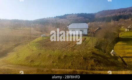 Vue sur le paysage d'un village de montagne dans les Carpates à l'automne de la fenêtre du train. Vue depuis un vieux train d'un village de montagne. Banque D'Images