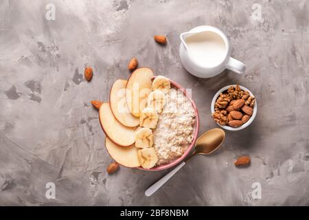 Bol avec flocons d'avoine sucrés savoureux, noix et lait sur fond grunge Banque D'Images