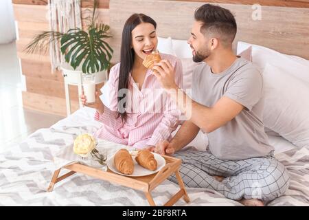 Couple jeune avec petit déjeuner au lit à la maison Banque D'Images