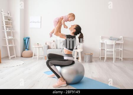 Jeune mère sportive et son bébé font des exercices avec le fair à la maison Banque D'Images