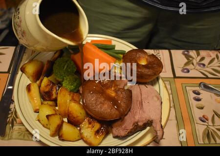 Sauce d'agneau versée le dimanche. Vin rouge et farine de plaine épaississent jus de viande dîner, y compris Yorkshire pudding pommes de terre poireaux panais haricots verts Banque D'Images