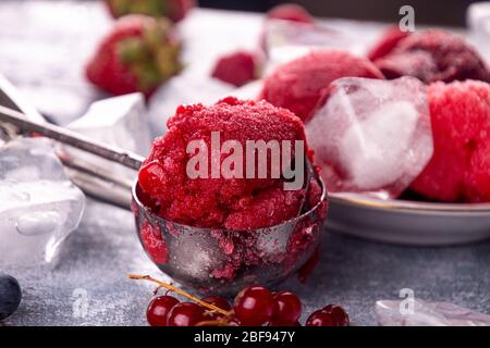 Boule de fraise maison, cassis rouge, framboise, crème glacée aux bleuets, sorbet.in pelle. Baies sur fond de bois. Dessert d'été, sn doux Banque D'Images