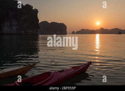 Deux kayaks profitant du coucher du soleil sur les falaises de calcaire de la baie de Halong. Banque D'Images