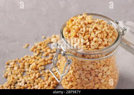 Grains de pois secs dans un bocal en verre sur fond gris, gros plan, espace de copie Banque D'Images