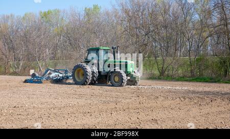 Nagybajcs Hongrie 04 04 2020: Un grand tracteur John Deere 4755 moderne avec roues doubles va dans le champ. Le tracteur cultive le sol. Banque D'Images