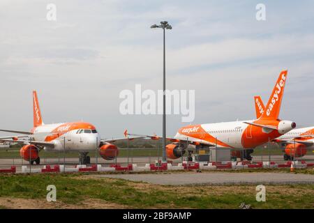 Southend-on-Sea, Royaume-Uni. 17 avril 2020. Plusieurs avions EasyJet stationnés sur le tarmac de l'aéroport de Londres Southend, Essex, Angleterre. Les avions arborent la signature orange et blanche de la compagnie aérienne. Des barrières rouges et blanches et un haut poteau lumineux sont visibles au premier plan, avec des zones herbeuses et un ciel nuageux en arrière-plan. Les avions easyJet sont assis sur la piste de l’aéroport de Southend à la suite des mesures prises par les États européens et les principales compagnies aériennes européennes, en réponse à la pandémie de COVID-19. Penelope Barritt/Alamy Live News Banque D'Images