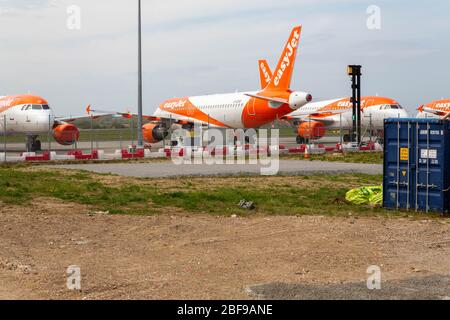Southend-on-Sea, Royaume-Uni. 17 avril 2020. Une série d'avions EasyJet stationnés sur le tarmac de l'aéroport de Londres Southend, Essex. L’avion arbore la décoration orange et blanche de la compagnie aérienne, positionnée derrière des barricades de sécurité avec un conteneur bleu et un premier plan herbeux. Les avions easyJet sont assis sur la piste de l’aéroport de Southend à la suite des mesures prises par les États européens et les principales compagnies aériennes européennes, en réponse à la pandémie de COVID-19. Penelope Barritt/Alamy Live News Banque D'Images