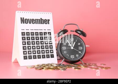 Réveil, calendrier et pièces sur fond couleur. Concept de gestion du temps Banque D'Images