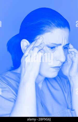 Infirmière ou médecin stressé et surtravaillé souffrant d'une attaque aiguë de maux de tête ou de migraine, effet de filtre bleu Banque D'Images