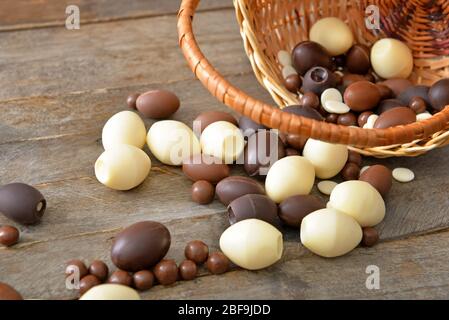 Panier avec œufs et bonbons au chocolat sur table en bois Banque D'Images