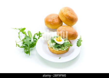 Pain maison avec fromage à tartiner, roquette fraîche et oeuf cuit dans une plaque isolée sur fond blanc Banque D'Images