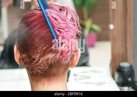 Les mains de coiffeur saupoudrer d'eau sur les cheveux roses de la femme dans le salon de coiffure. Banque D'Images