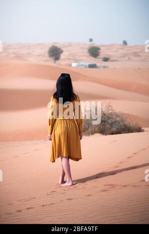 Femme marchant dans un désert avec une vue arrière ensoleillée Banque D'Images