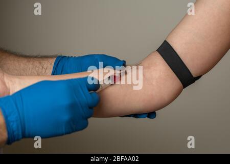 un médecin en gants jetables prend du sang de la veine du patient pour analyse Banque D'Images